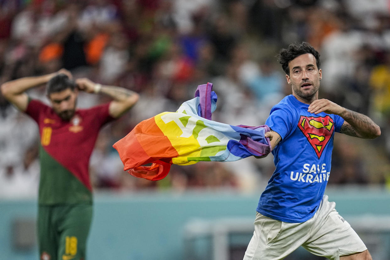 A pitch invader runs across the field with a rainbow flag during the World Cup group H soccer match between Portugal and Uruguay, at the Lusail Stadium in Lusail, Qatar, Monday, Nov. 28, 2022. (AP Photo/Abbie Parr)