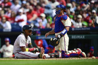 Atlanta Braves' Ronald Acuña Jr., left, adjusts his gear in front of Philadelphia Phillies' J.T. Realmuto after a close pitch during the sixth inning of a baseball game Sunday, March 31, 2024, in Philadelphia. (AP Photo/Derik Hamilton)