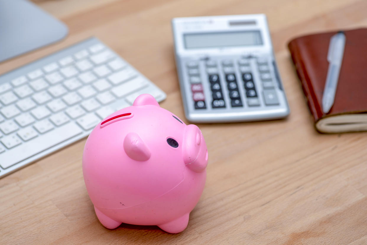 Savings and investment concept, pink piggy bank with calculator on pile or economic analysis report chart and graph on office table.