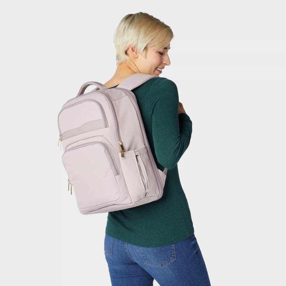 A model wearing the backpack in taupe