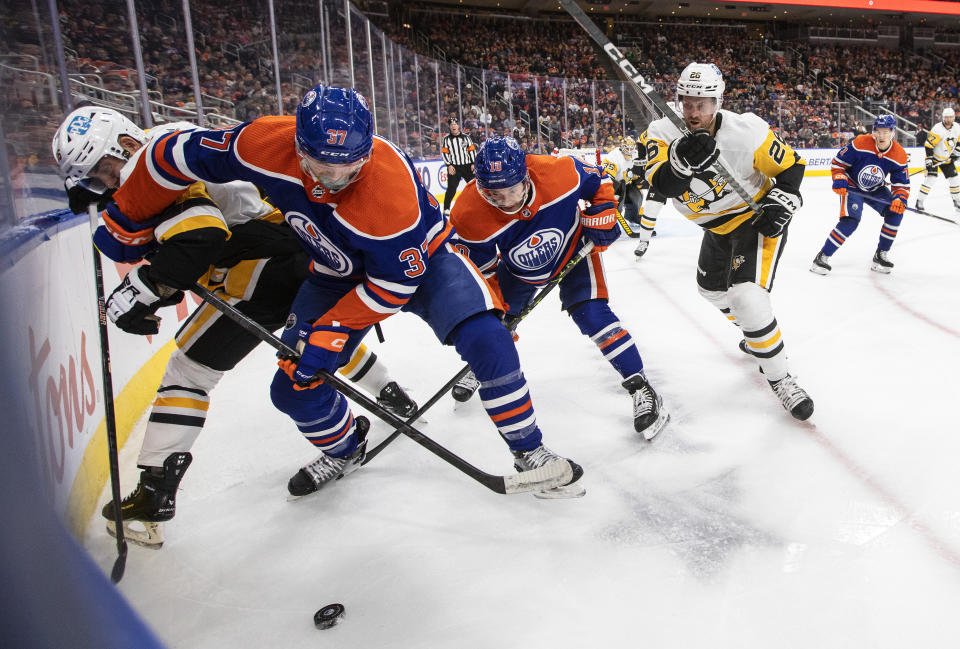 Pittsburgh Penguins' Jason Zucker and Jeff Petry battle for the puck with Edmonton Oilers' Warren Foegele and Zach Hyman during the second period of an NHL hockey game in Edmonton, Alberta, on Monday, Oct. 24, 2022. (Jason Franson/The Canadian Press via AP)