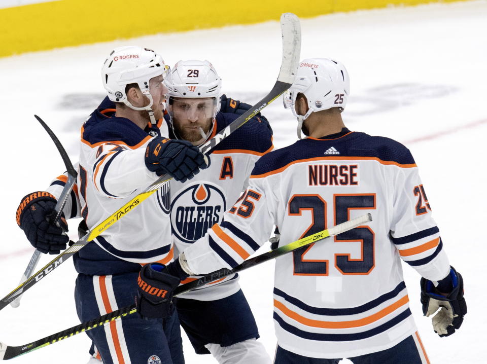 Edmonton Oilers center Leon Draisaitl (29) is congratulated by teammates Connor McDavid (97) and Darnell Nurse (25) after scoring against the Toronto Maple Leafs during second-period NHL hockey game action in Toronto, Saturday, March 27, 2021. (Frank Gunn/The Canadian Press via AP)