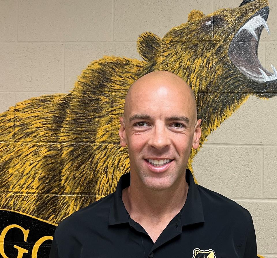 Ryan Hill in front of a picture of the Golden Bears mascot at Mt. Juliet High. Hill is the principal at Mt. Juliet High where he attended.