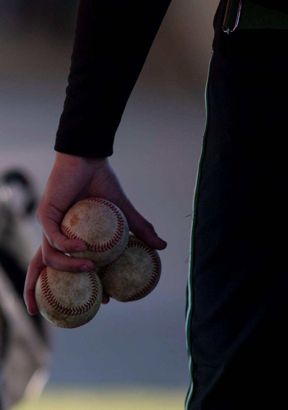 A North High School baseball player collects baseballs after warmups before the game against the Mount Vernon Wildcats at Mount Vernon High School in Mount Vernon, Ind., Friday night, April 1, 2022. One dozen game-quality baseballs now cost about $87. Teams and coaches are making sure to get the most out of each ball. 