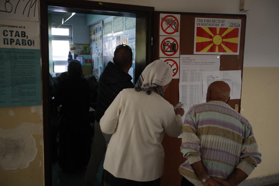 People check a board to locate their polling stations in order to vote during a referendum in Skopje, Macedonia, Sunday, Sept. 30, 2018. Macedonians were deciding Sunday on their country's future, voting in a crucial referendum on whether to accept a landmark deal ending a decades-old dispute with neighbouring Greece by changing their country's name to North Macedonia, paving the way to NATO membership.(AP Photo/Thanassis Stavrakis)