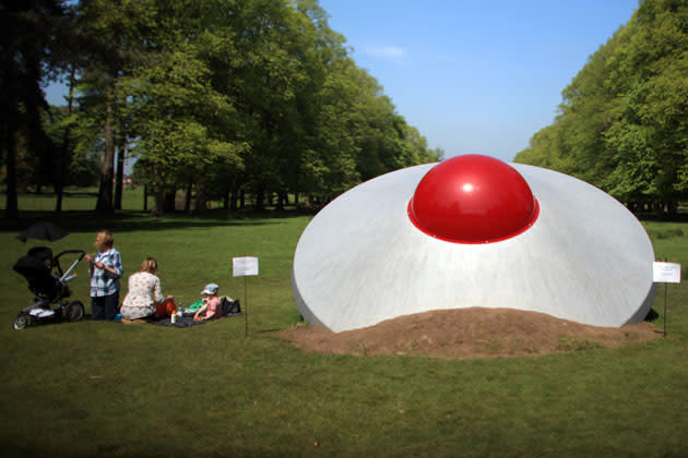 A family take a picnic next to a crashed flying saucer, an artwork entitled 'Vex' by artist Dinu Li, at Tatton Park as part of the 2012 Tatton Biennial on May 21, 2012 in Knutsford, England. This years exhibition explores 'Flights of Fancy' and displays the work of more than 20 artists at the National Trust property in Cheshire. The exhibition runs until September. (Photo by Christopher Furlong/Getty Images)