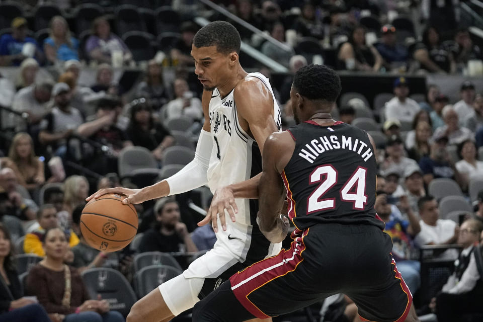 San Antonio Spurs center Victor Wembanyama (1) drives around Miami Heat forward Haywood Highsmith (24) during the second half of a preseason NBA basketball game in San Antonio, Friday, Oct. 13, 2023. (AP Photo/Eric Gay)