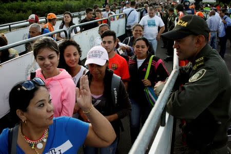 A Colombian police officer looks on as people line up to cross over the Simon Bolivar international bridge to Colombia to take advantage of the temporary border opening in San Antonio del Tachira, Venezuela, July 17, 2016. REUTERS/Carlos Eduardo Ramirez