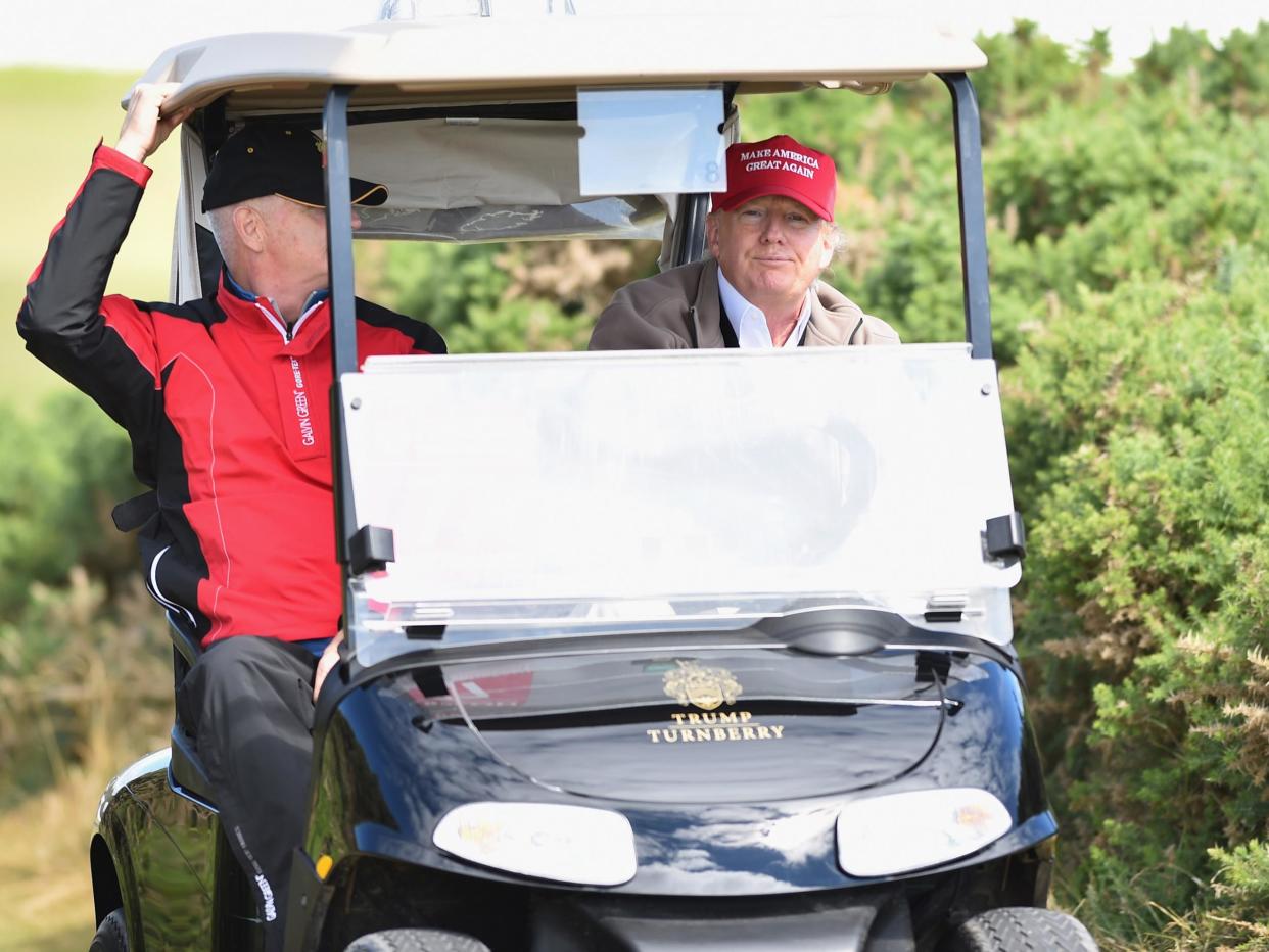 Donald Trump drives a golf buggy during his visits to his Scottish golf course Turnberry in 2016: Trump in a golf buggy during a visit to his Scottish golf course in 2016