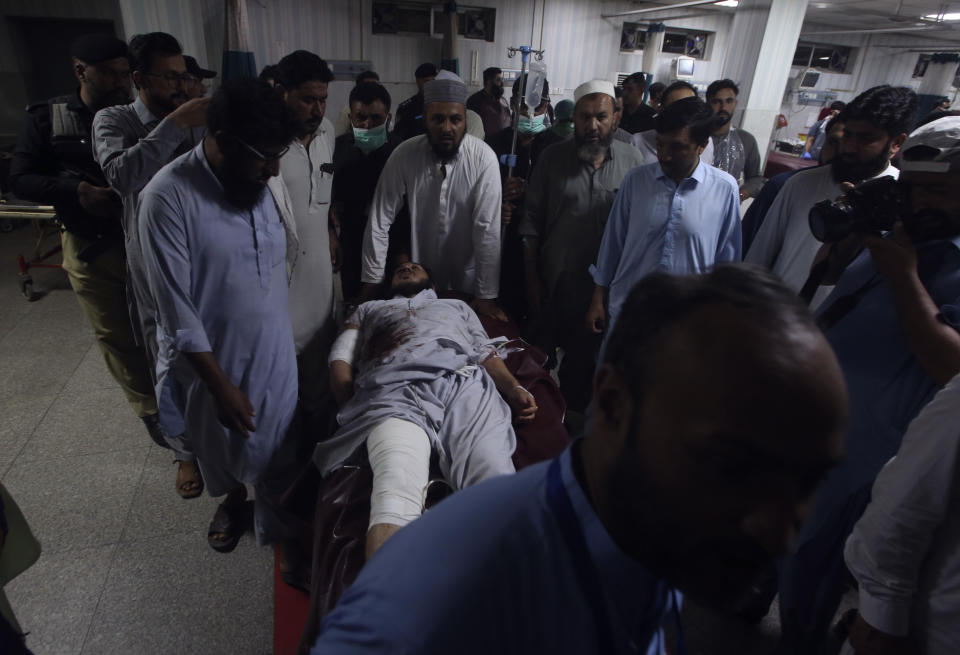 Health workers and people transport an injured victim of a powerful bomb upon arrival at a hospital in Peshawar, Pakistan, Sunday, July 30, 2023. A bomb ripped through a rally by supporters of a hard-line cleric and political leader in the country's northwestern Bajur district that borders Afghanistan on Sunday, police and health officials said. (AP Photo/Muhammad Sajjad)