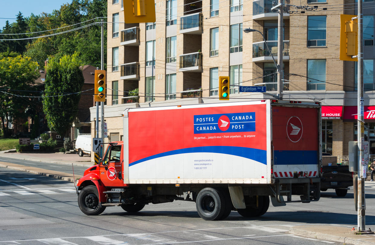 TORONTO, ONTARIO, CANADA - 2015/08/13: Red and white color Canada Post delivery truck passing through a traffic junction. Canada Post or  Postes Canada, is the crown corporation which functions as the country's primary postal operator. It was earlier known as Royal Mail Canada. (Photo by Roberto Machado Noa/LightRocket via Getty Images)