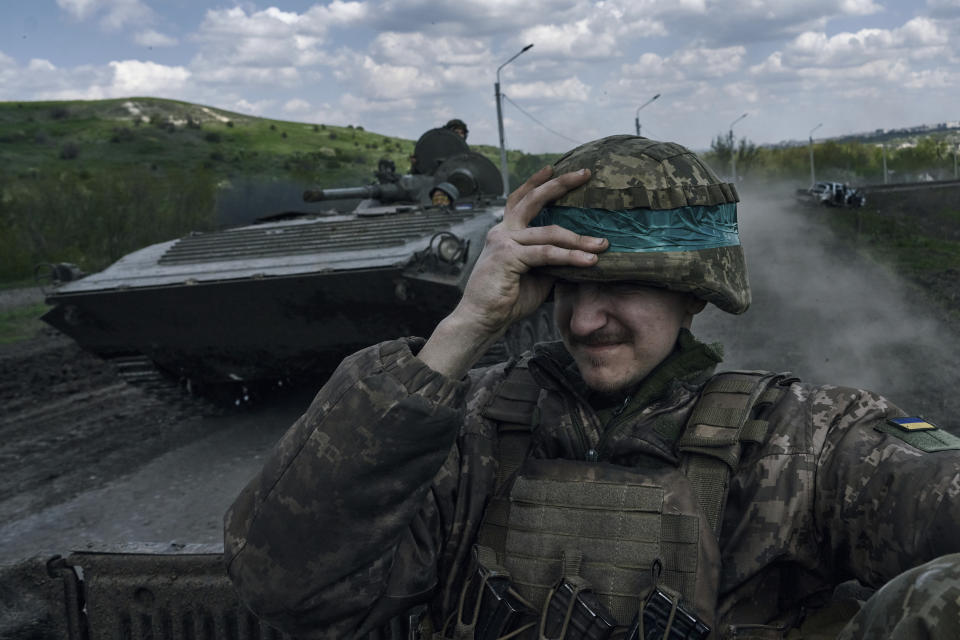 FILE - A Ukrainian soldier holds his helmet as he rides an APC in Bakhmut, in the Donetsk region, Ukraine, Wednesday, April 26, 2023. Ukrainian President Volodymyr Zelenskyy said Sunday, May 21, 2023 that Russian forces weren't occupying Bakhmut, casting doubt on Moscow's insistence that the eastern Ukrainian city had fallen. The fog of war made it impossible to confirm the situation on the ground in the invasion’s longest battle, and the comments from Ukrainian and Russian officials added confusion to the matter. (AP Photo/Libkos, File)