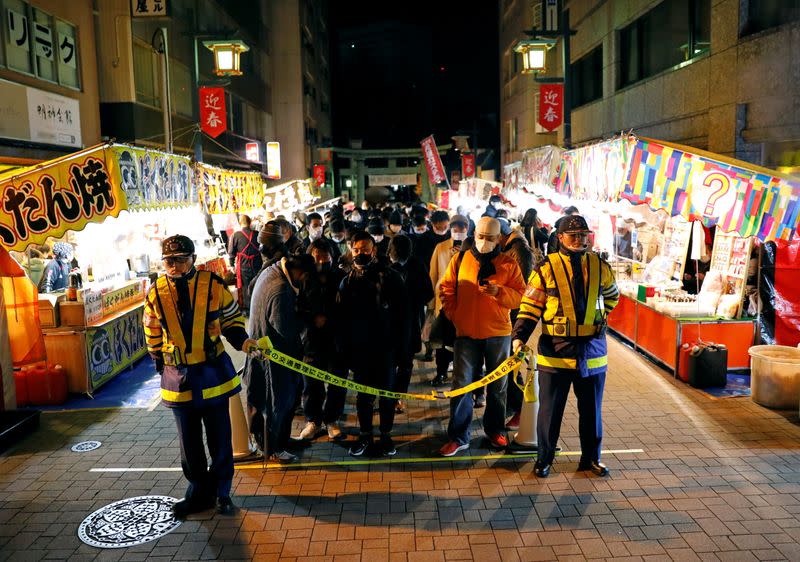 People wearing protective face masks wait in front of main gate to offer prayers for the New Year at the Kanda Myojin shrine, in Tokyo