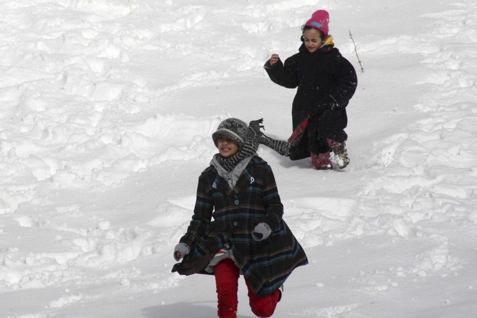 Children play with snow after a heavy snowstorm in Amman December 13, 2013. A powerful winter storm sweeping the eastern Mediterranean this week is causing mayhem across the region. The storm, named Alexa, is expected to last until Saturday, bringing more snow, rain and freezing temperatures to large swathes of Turkey, Syria, Lebanon, Jordan, Israel and the Palestinian territories. REUTERS/Majed Jaber (JORDAN - Tags: ENVIRONMENT SOCIETY)