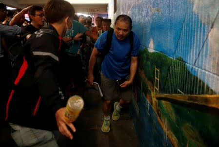 People create a passageway for a pro-government supporter to leave after he was beaten up by anti-extradition supporters outside the office of pro-China lawmaker Junius Ho in Tsuen Wan