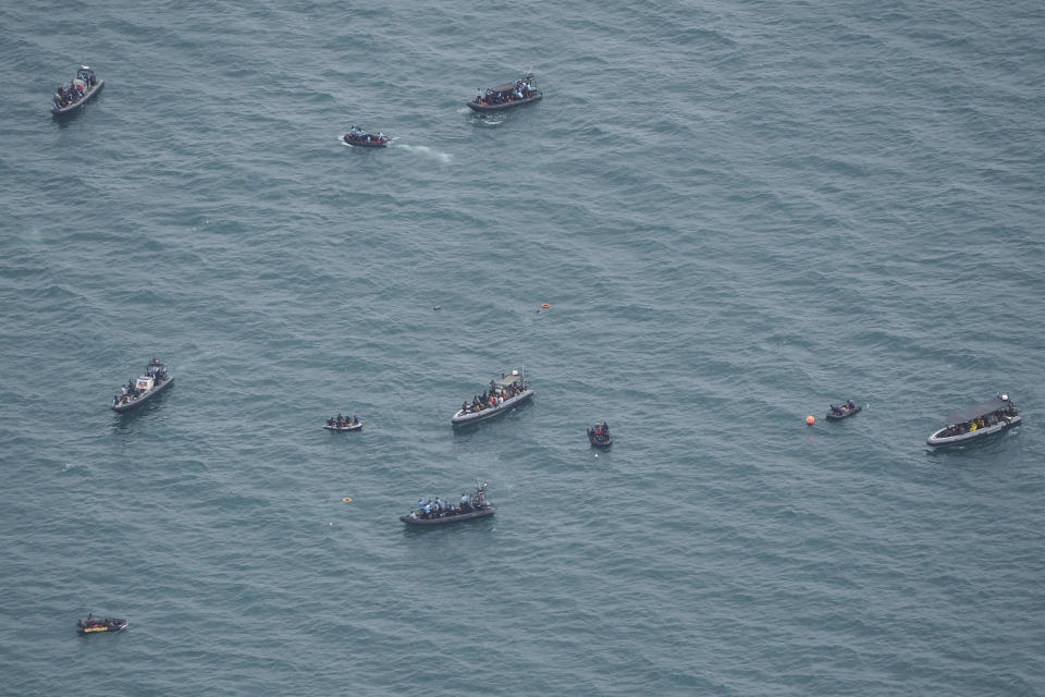 Rubber boats carrying divers position themselves as the search for the wreckage of a crashed Sriwijaya Air passenger jet continues, in this photo taken from an Indonesian Navy airplane over the Java Sea, off Jakarta, Indonesia, Tuesday, Jan. 12, 2021. Indonesian navy divers were searching through plane debris and seabed mud Tuesday looking for the black boxes of the Sriwijaya Air jet that nosedived into the Java Sea over the weekend with 62 people aboard. (AP Photo/Eric Ireng)
