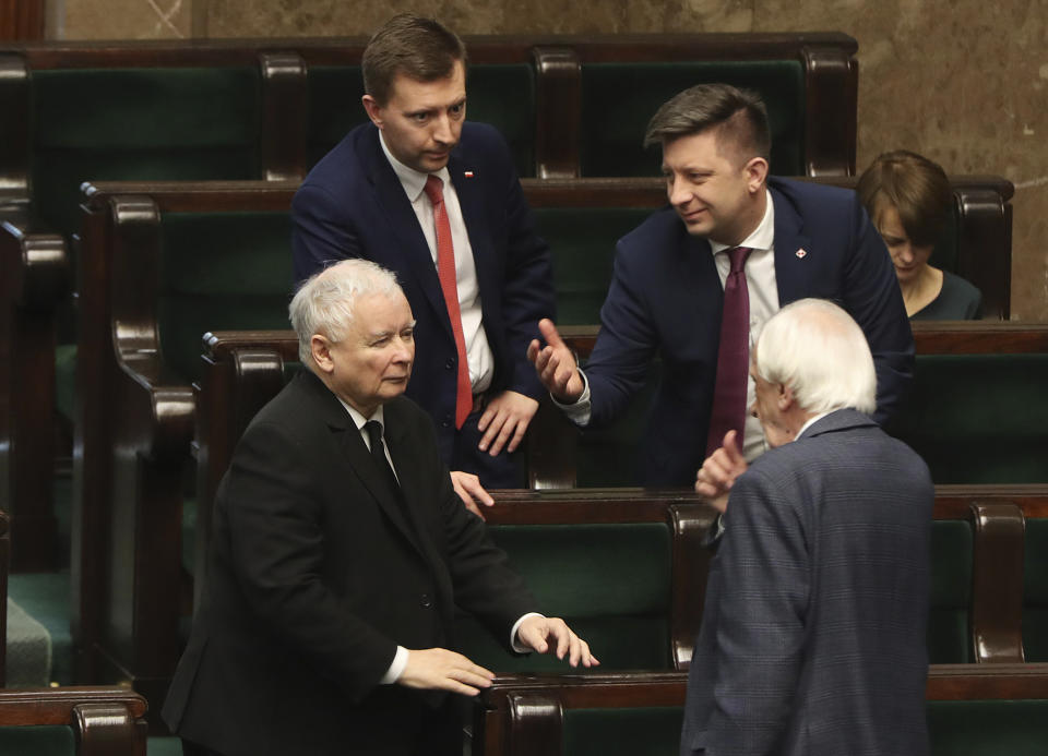 Jaroslaw Kaczynski,left, leader of the conservative ruling party Law and Justice, speaks with other members of his party in parliament in Warsaw, Poland, Friday April 3, 2020. Uncertainty deepened in Poland on Friday over whether the country will move forward with a presidential election scheduled for May despite the coronavirus pandemic. Kaczynski had hoped to move forward with the vote despite the epidemic by having a postal election, but the head of a faction in his coalition is opposed and wants the elections postponed by two years.(AP Photo/Czarek Sokolowski)