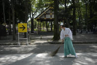 Workers sweep the area along the men's cycling road race prior to its start, outside the Okunitama Shrine, at the 2020 Summer Olympics, Saturday, July 24, 2021, in Fuchu, Japan. (AP Photo/Christophe Ena)