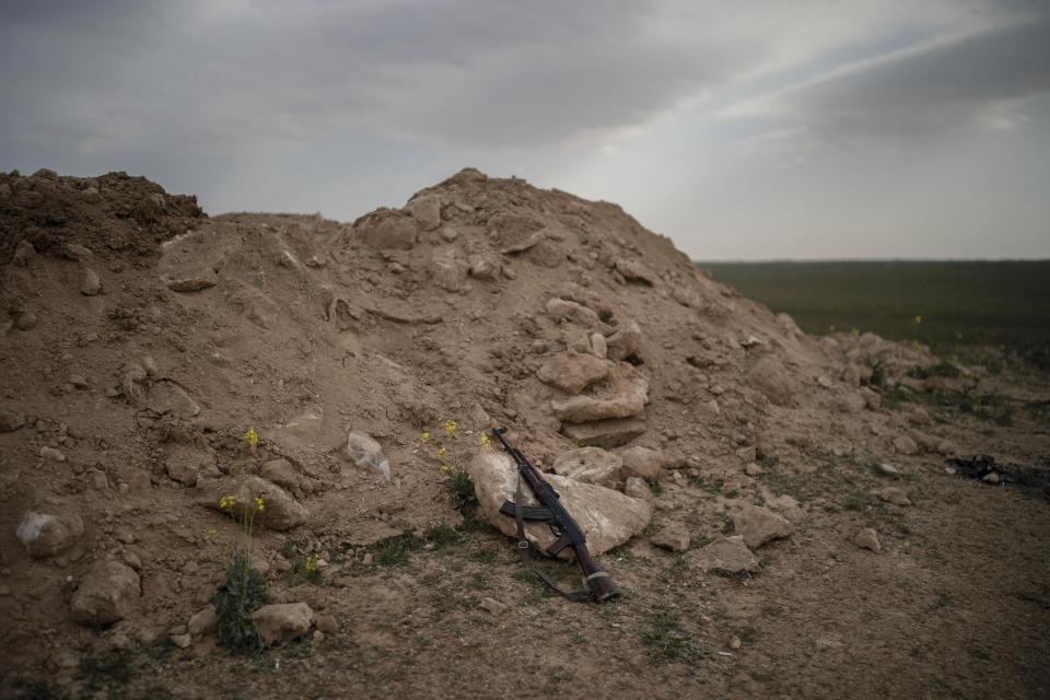 An AK-47 rifle, belonging to a U.S.-backed Syrian Democratic Forces (SDF) fighter, rests on a rock on a hill in the desert outside the village of Baghouz, Syria, Thursday, Feb. 14, 2019. U.S.-backed Syrian forces are clearing two villages in eastern Syria of remaining Islamic State militants who are hiding among the local population, and detaining others attempting to flee with the civilians, the U.S.-led coalition said Thursday. (AP Photo/Felipe Dana)