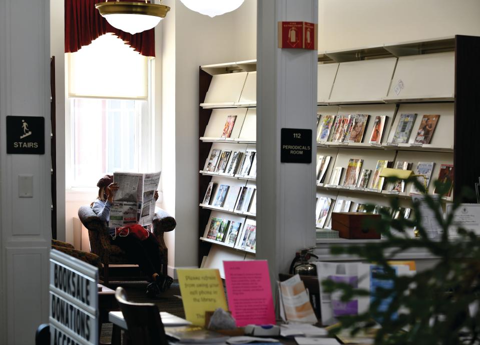 A patron reads the newspaper in the periodicals room of the Beaman Memorial Public Library.