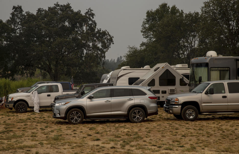 Vehicles are parked at the Green Valley Community Church evacuation shelter on Thursday, Aug. 19, 2021, in Placerville, Calif., as the Caldor Fire continues to burns. (AP Photo/Ethan Swope)