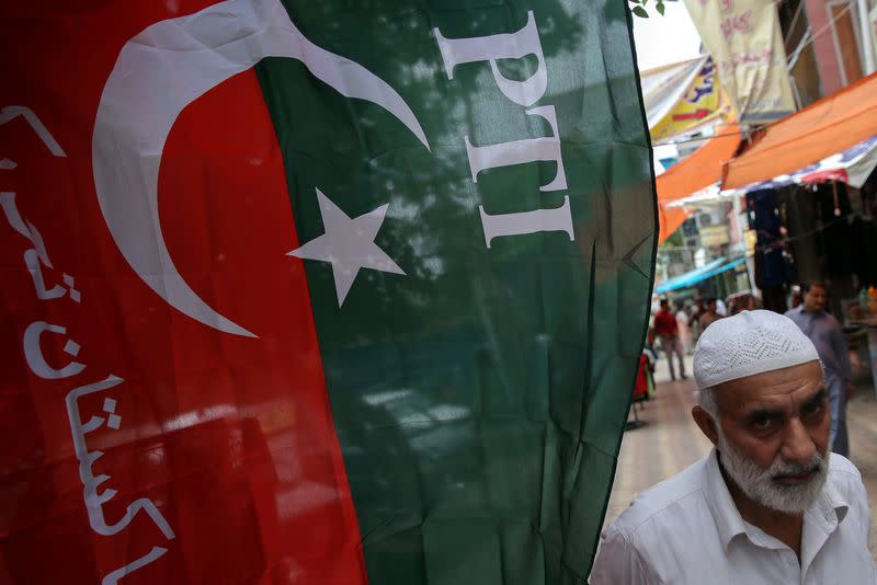 A man walks past a flag of the Pakistan Tehreek-e-Insaf (PTI) at a market, a day after general election in Islamabad