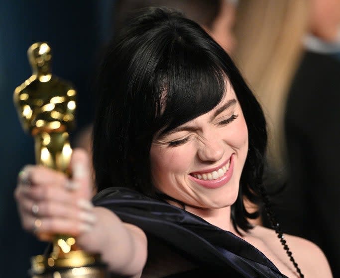 Billie smiles with her eyes shut as she holds her Oscar