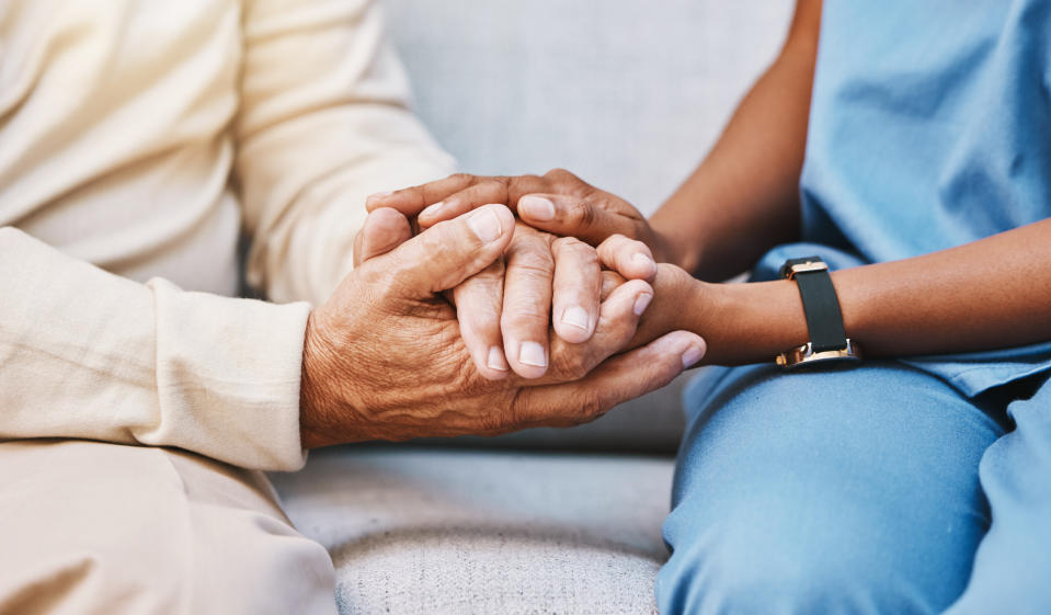 Two individuals holding hands in a comforting gesture, close-up on hands