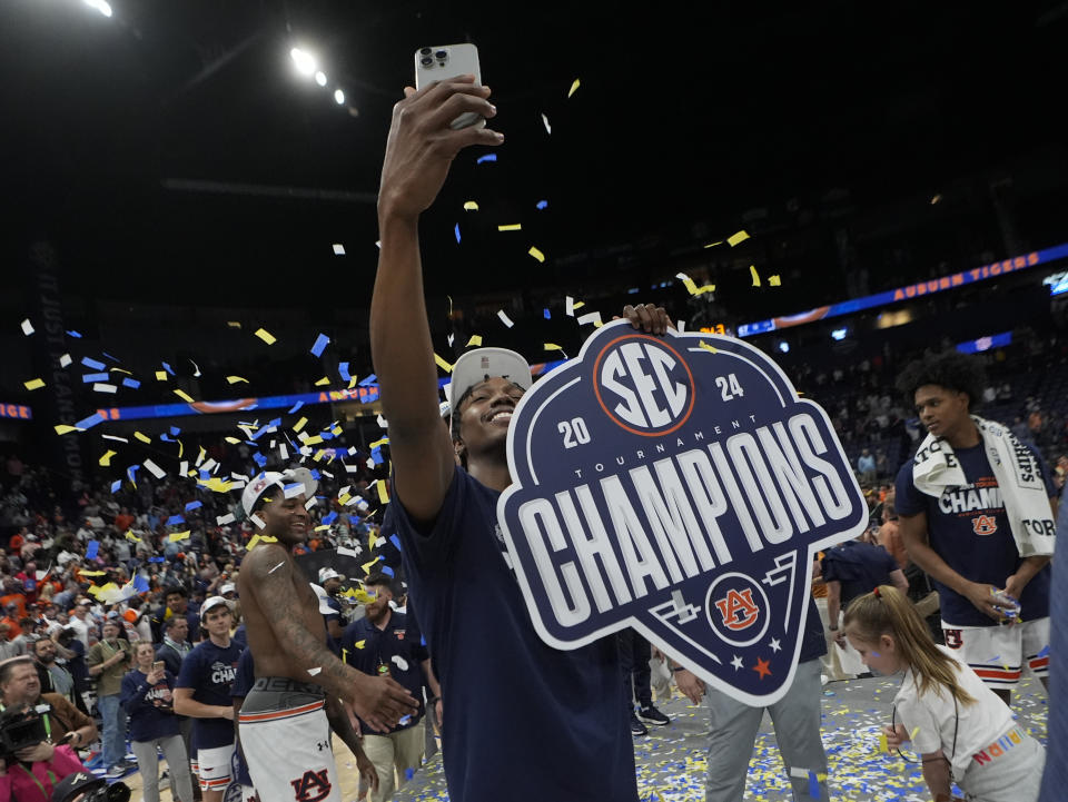Auburn guard Denver Jones (12) takes a photo after defeating Florida in an NCAA college basketball game to win the Southeastern Conference tournament Sunday, March 17, 2024, in Nashville, Tenn. (AP Photo/John Bazemore)
