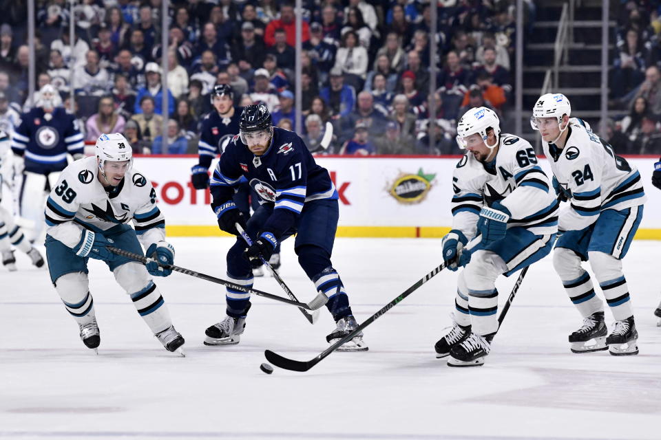 Winnipeg Jets' Adam Lowry (17) and San Jose Sharks' Logan Couture (39), Erik Karlsson (65) and Jacob Peterson (24) try to control the puck during second-period NHL hockey game action in Winnipeg, Manitoba, Monday April 10, 2023. (Fred Greenslade/The Canadian Press via AP)