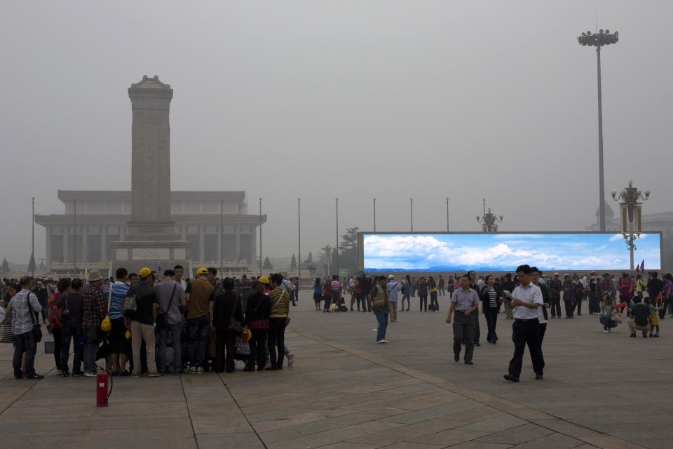 In this photo taken on Sept. 13, 2013 tourists visit Tiananmen Square on a hazy day while an electronic screen shows a blue sky and white clouds as part of a propaganda video in Beijing, China. China’s tourism industry has grown at a fast pace since the country began free market-style economic reforms three decades ago. However, it's latest tourism slogan "Beautiful China" has been derided as particularly inept at a time when record-busting smog has drawn attention to the environmental and health costs of China’s unfettered industrialization. Some point to unsophisticated marketing as an explanation. (AP Photo/Alexander F. Yuan)