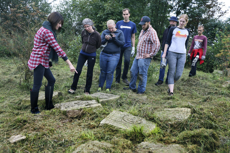 In this photo taken on Aug. 29, 2018, U.S. citizen Marla Raucher Osborn, a Rohatyn Jewish heritage project leader, left, shows volunteers the gravestones at an old Jewish cemetery in Rohatyn close to Lviv, Ukraine, a few days before the 75th anniversary of the annihilation of the city's Jewish population by Nazi Germany. The commemoration comes amid a larger attempt in Ukraine to remember and celebrate the lost Jewish world in a part of Ukraine that before World War II was part of Poland and was the third largest Polish Jewish community. (AP Photo/Yevheniy Kravs)