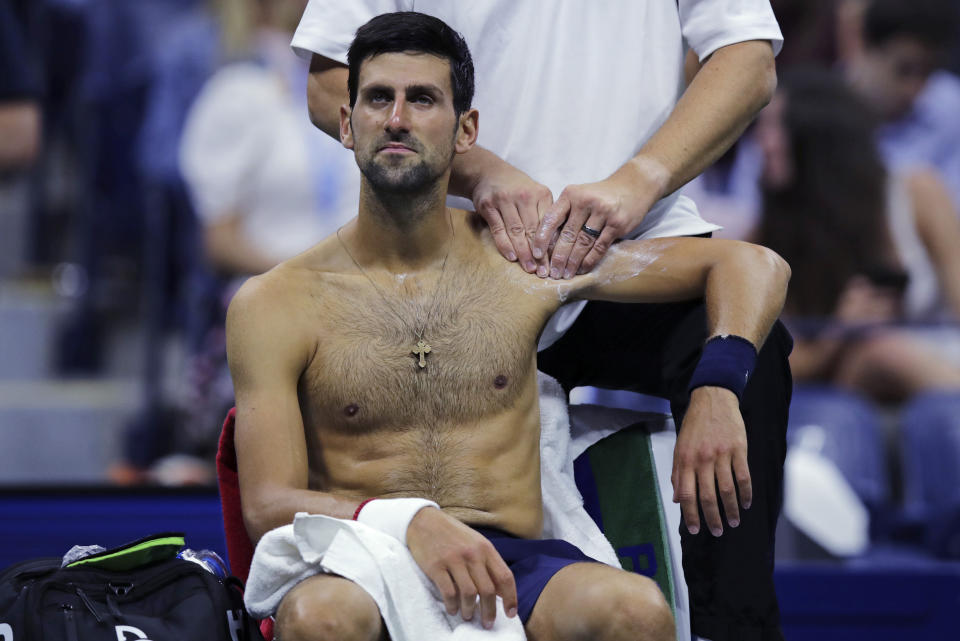 Novak Djokovic, of Serbia, receives treatment from a trainer during his match against Juan Ignacio Londero, of Argentina, during the second round of the U.S. Open tennis tournament in New York, Wednesday, Aug. 28, 2019. (AP Photo/Charles Krupa)