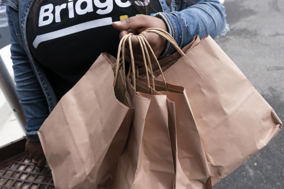 A volunteer distributes bags of produce and hot and cold lunch meals, at the Town Hall Education Arts & Recreation Campus (THEARC), Wednesday, Oct. 6, 2021, in Washington. (AP Photo/Jacquelyn Martin)