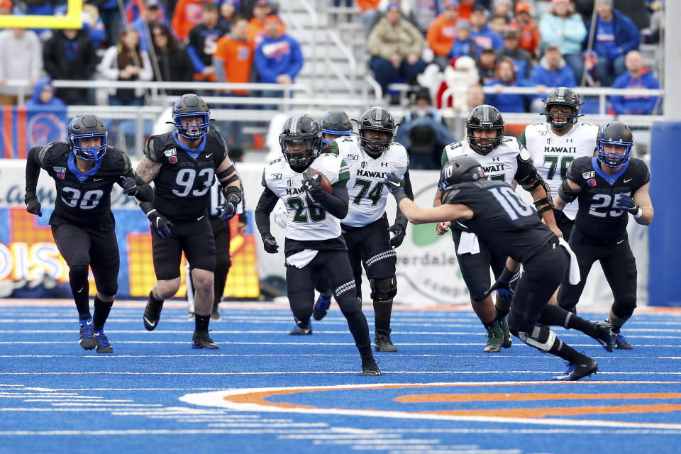 Hawaii running back Miles Reed, center, breaks away from the Boise State defense on a 25 yard run during the first half of an NCAA college football game for the Mountain West Championship Saturday, Dec. 7, 2019, in Boise, Idaho. (AP Photo/Steve Conner)