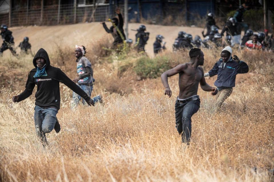 Migrants run across Spanish soil in Melilla after crossing the border checkpoint (AP)