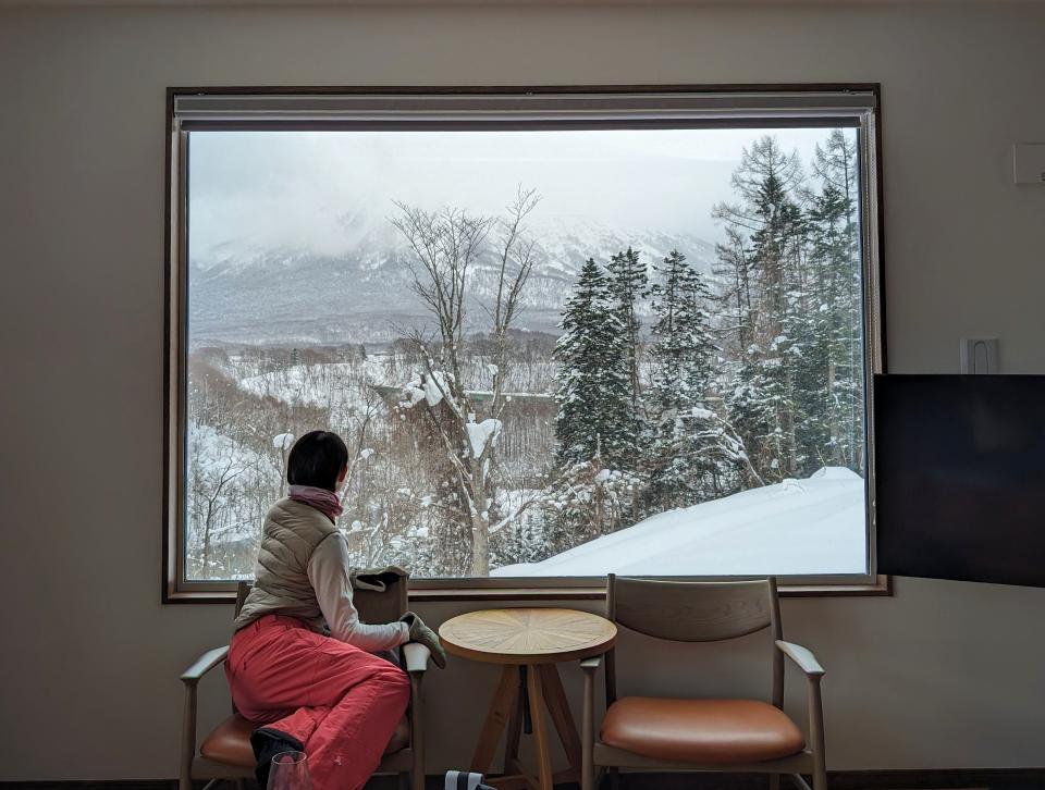 Woman looking out the window at ski chalet in Niseko, Japan