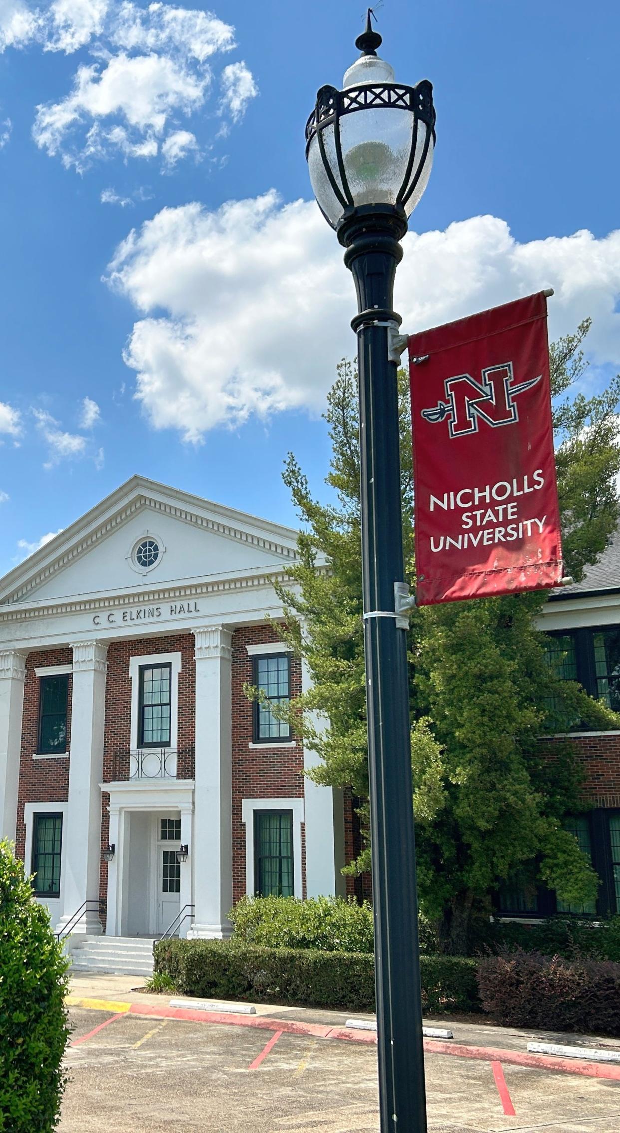 A flag displaying Nicholls State University's logo hangs in front of the Elkins Hall administration building on the Thibodaux campus.