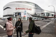 FILE - In this March 12, 2020, file photo, people talk outside Rogers Place, the home ice of the NHL hockey club Edmonton Oilers, in Edmonton, Alberta. Rogers Place is one of the possible locations the NHL has zeroed in on to host playoff games if it can return amid the coronavirus pandemic. The league will ultimately decide on two or three locations for games, with government regulations, testing and COVID-19 frequency among the factors for the decision that should be coming within the next three to four weeks.(Jason Franson/The Canadian Press via AP, File)