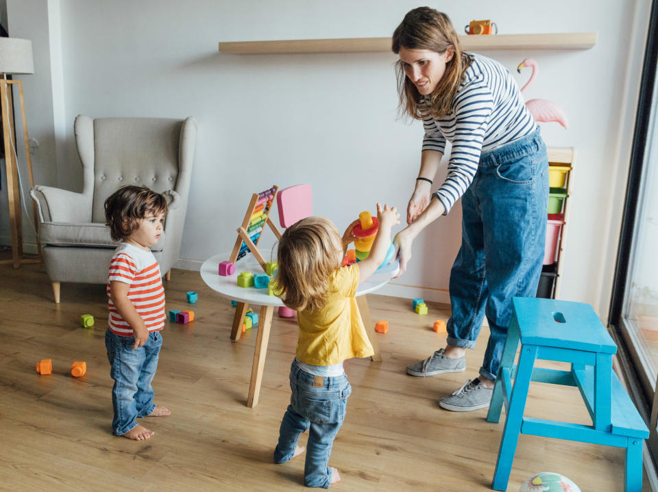 A woman playing with two toddlers