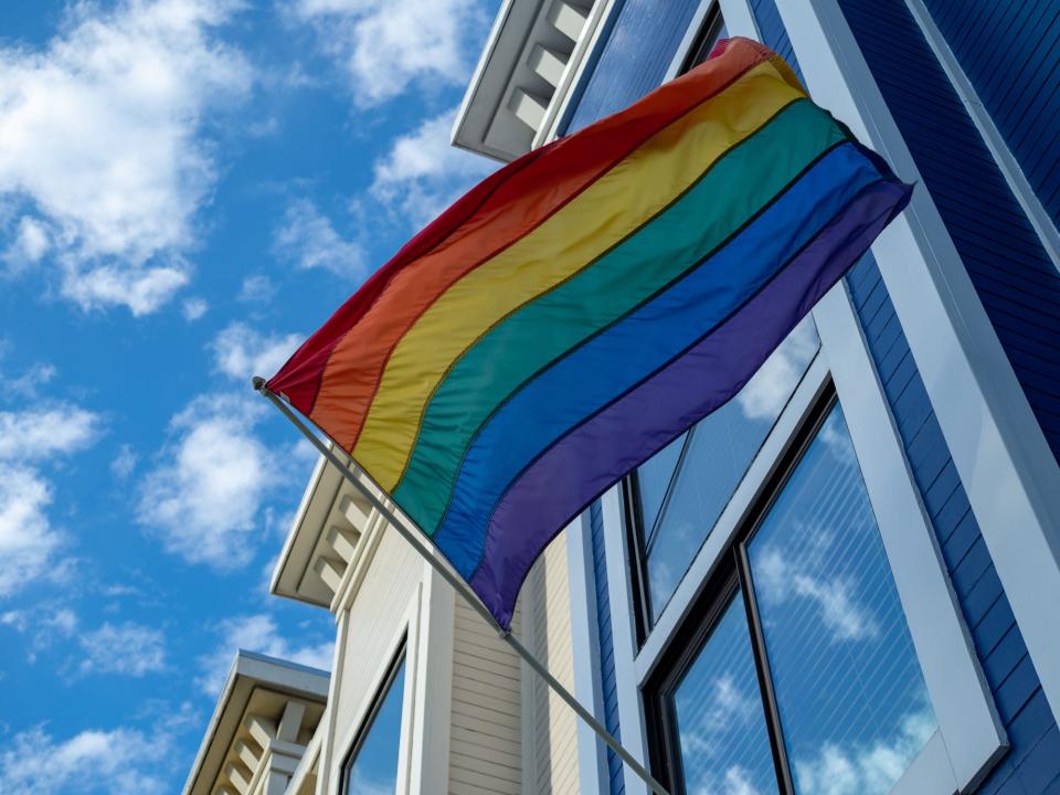 Upward view of gay pride, LGBT flag hanging outside of a house