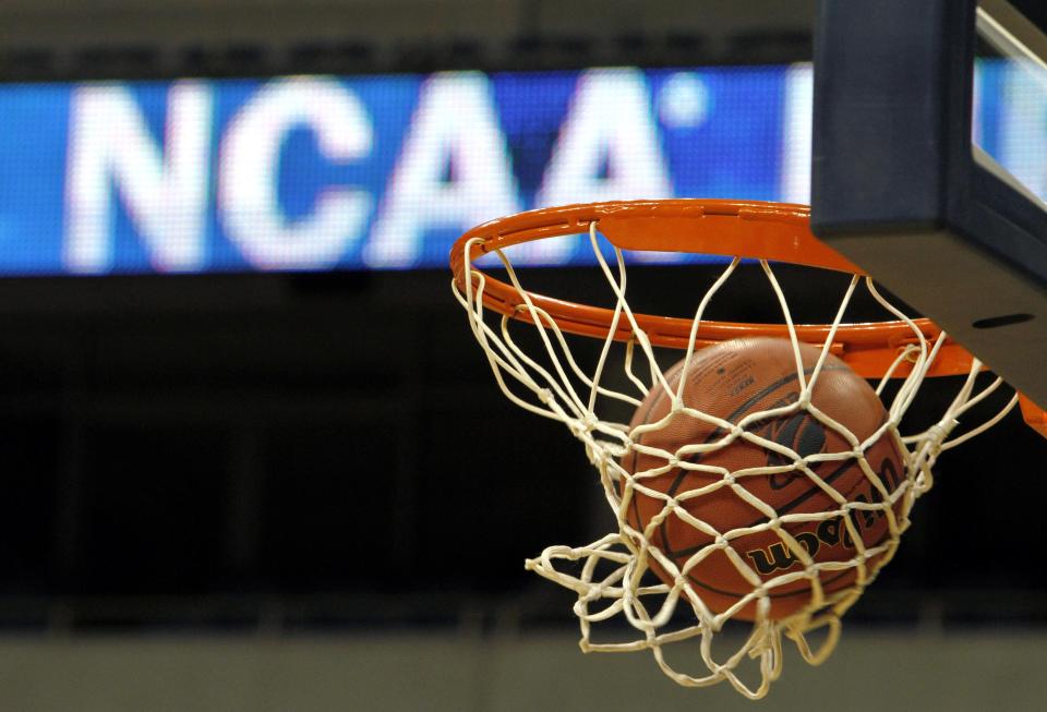 FILE - In this March 20, 2010, file photo, a ball flicks through the net in front of the NCAA logo on the marquis during an NCAA college basketball practice in Pittsburgh. Defying the NCAA, California's governor signed a first-in-the-nation law Monday, Sept. 30, that will let college athletes hire agents and make money from endorsements — a move that could upend amateur sports in the U.S. and trigger a legal challenge. (AP Photo/Keith Srakocic, File)