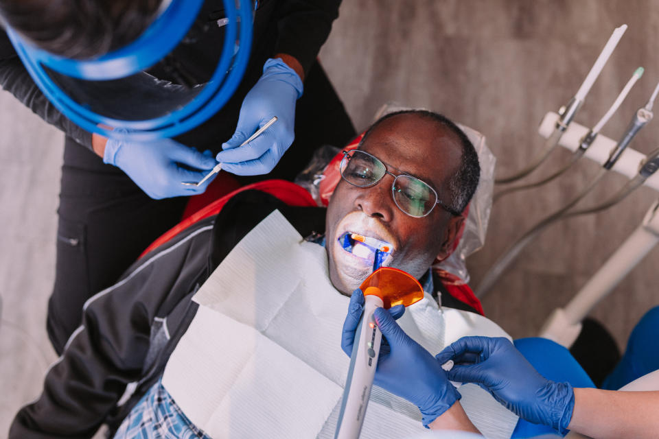 Person receiving dental treatment with protective eyewear, dentist and assistant working with equipment