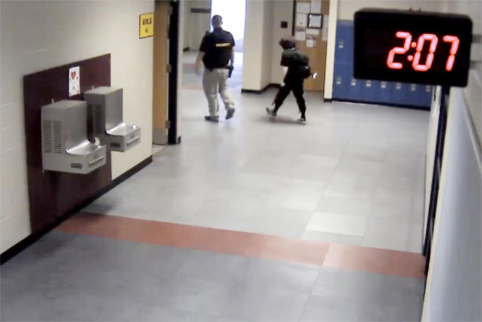 In this image taken from video taken from a school security camera and provided by the Owasso Police Dept., Nex Benedict is seen walking out of the school with a security guard, Feb. 7, 2024, at Owasso High School in Owasso, Okla. A recently released police search warrant is revealing more details in the case of a Benedict, a nonbinary student, who died a day after a high school bathroom fight. (School Security Video/Courtesy of Owasso Police Department via AP)