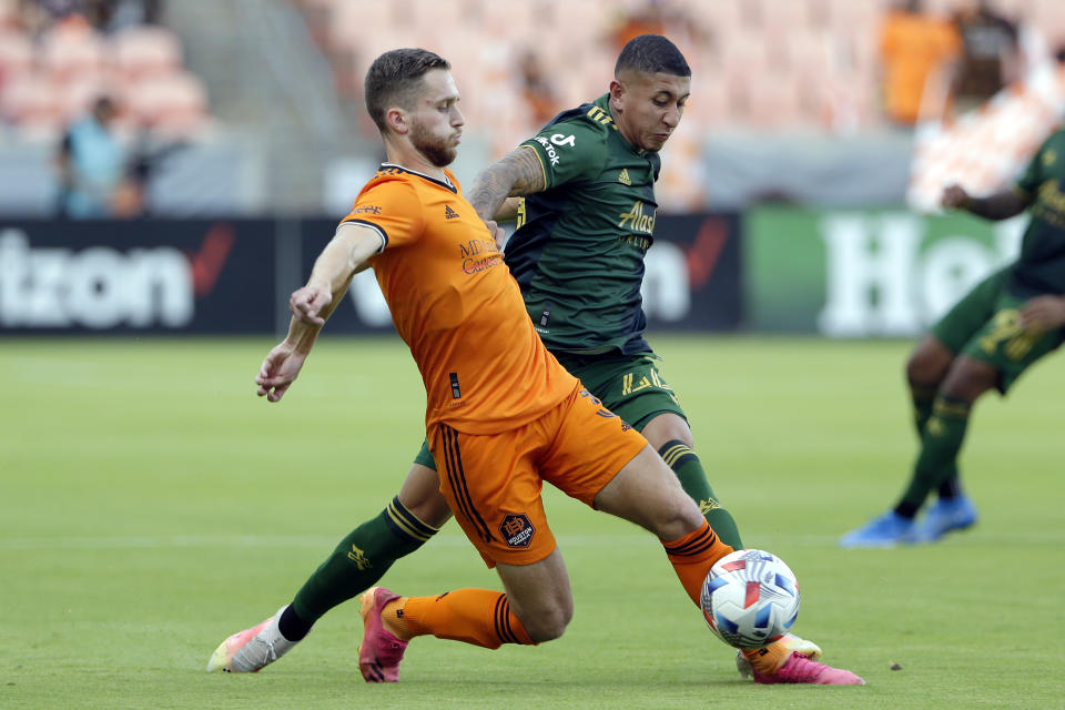 Houston Dynamo defender Adam Lundqvist, left, and Portland Timbers midfielder Marvin Loria, right, battle for the ball during the first half of an MLS soccer match Wednesday, June 23, 2021, in Houston. (AP Photo/Michael Wyke)