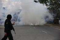 epa04044217 A Filipino policeman from the Special Weapons And Tactics (SWAT) team looks at tear gas fired against informal settlers during a demolition of shanties at Sitio San Roque in Quezon City, east of Manila, Philippines, 27 January 2014. Throwing rocks, pillboxes, and even human waste, illegal settlers barricaded the demolition team in Baranggay Bagong Pag-asa. Four residents were arrested and twelve were reported injured. Residents report receiving cash from 300 to 450 US dollar in exchange for their voluntary relocation. Earlier, hundreds of the urban poor marched to the city hall in protest of the demolition that will pave the way for the rise of a business district. EPA/DENNIS M. SABANGAN