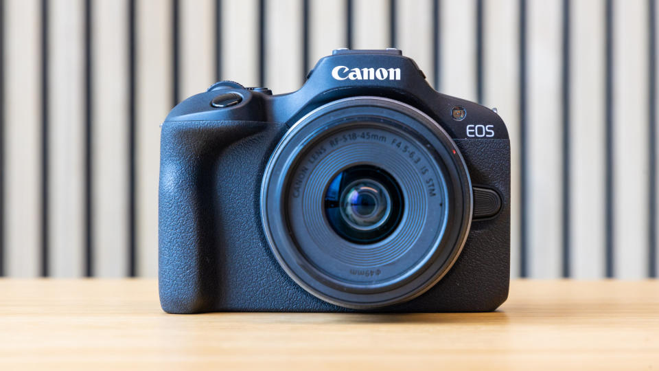 Canon EOS R100 camera on a table with a striped background