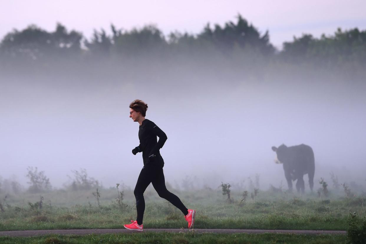 A woman runs past early morning mist along the River Cam in Cambridge on the day of the Autumn Equinox (Joe Giddens/PA)