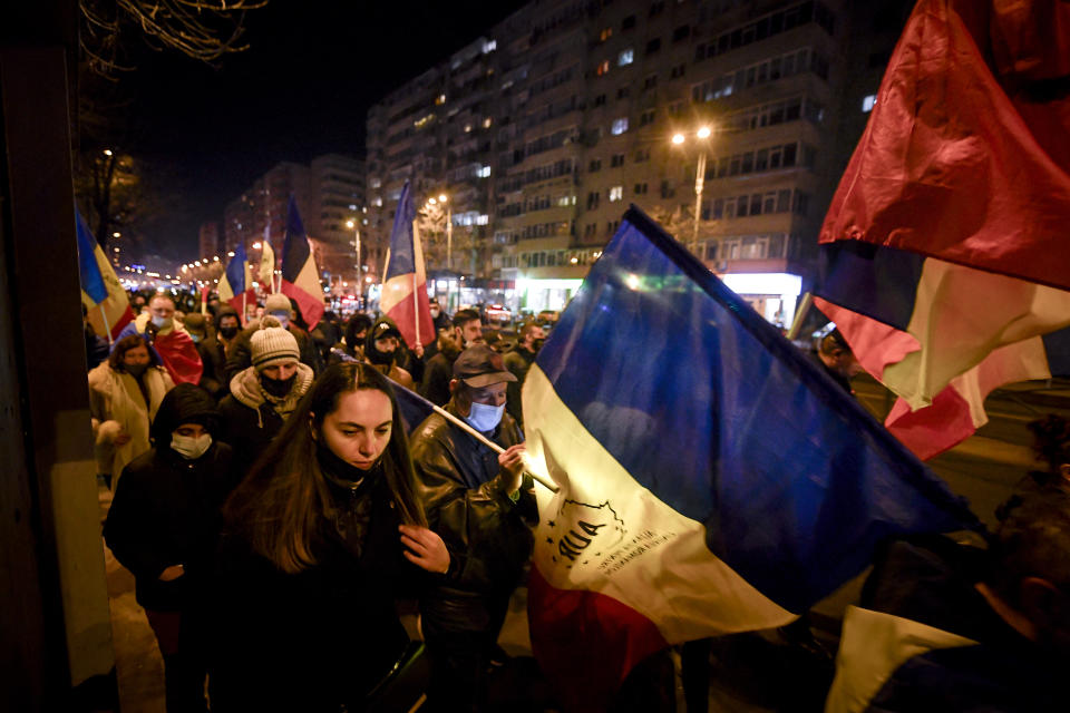 Protesters waving flags march after a deadly fire at a hospital treating COVID-19 patients in Bucharest, Romania, Saturday, Jan. 30, 2021. Hundreds marched during a protest organized by the AUR alliance demanding the resignation of several top officials, after a fire early Friday at a key hospital in Bucharest that also treats COVID-19 patients killed five people. (AP Photo/Andreea Alexandru)