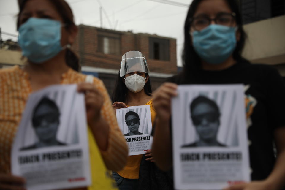 People hold photos of Jack Bryan Pintado Sanchez, a 22-year-old who died during weekend protests against lawmakers' removal of President Martin Vizcarra, outside the church holding his wake in Lima, Peru, Monday, Nov. 16, 2020, amid the COVID-19 pandemic. Peru's political turmoil took a turn Sunday when interim leader Manuel Merino quit and Congress couldn't decide on his replacement, leaving the nation without a president and in crisis less than a week after legislators removed Vizcarra. (AP Photo/Rodrigo Abd)